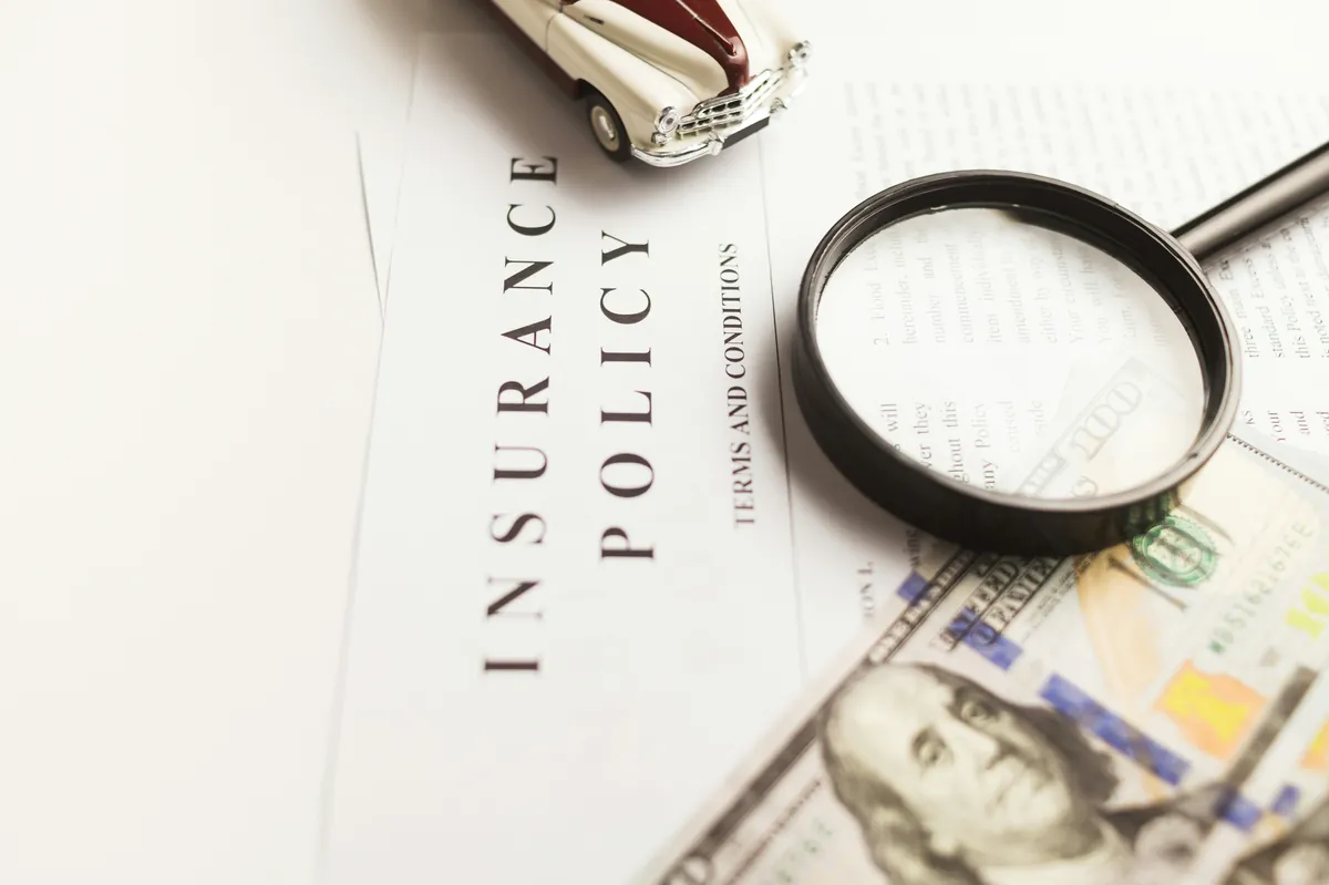 Insurance policy document reviewed with a magnifying glass, representing Carningham's thorough approach to cover